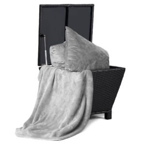 Black wicker side table with storage lid open showing cushions and blankets stored inside