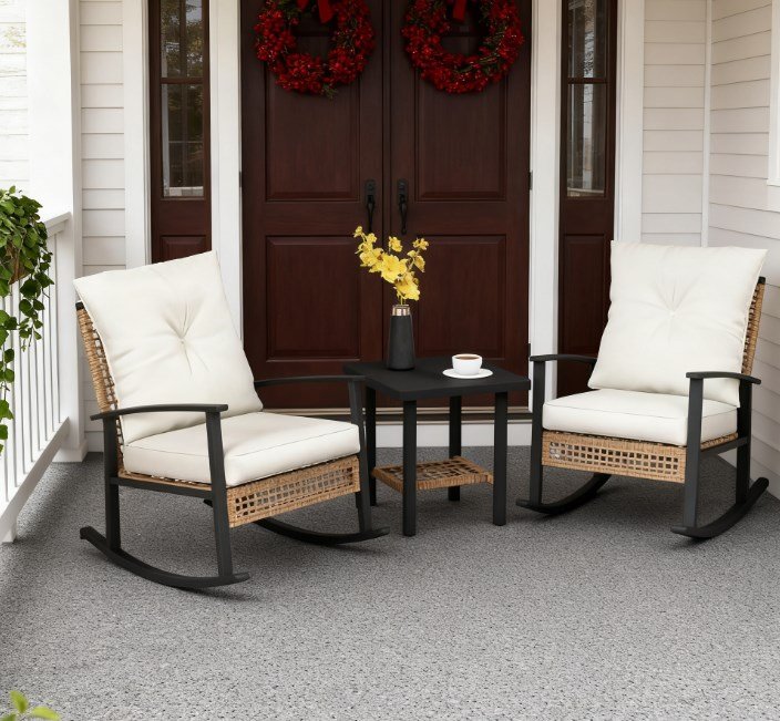 light yellow wicker rocking chair set with white cushions and coffee table placed on a front porch with flowers and coffee