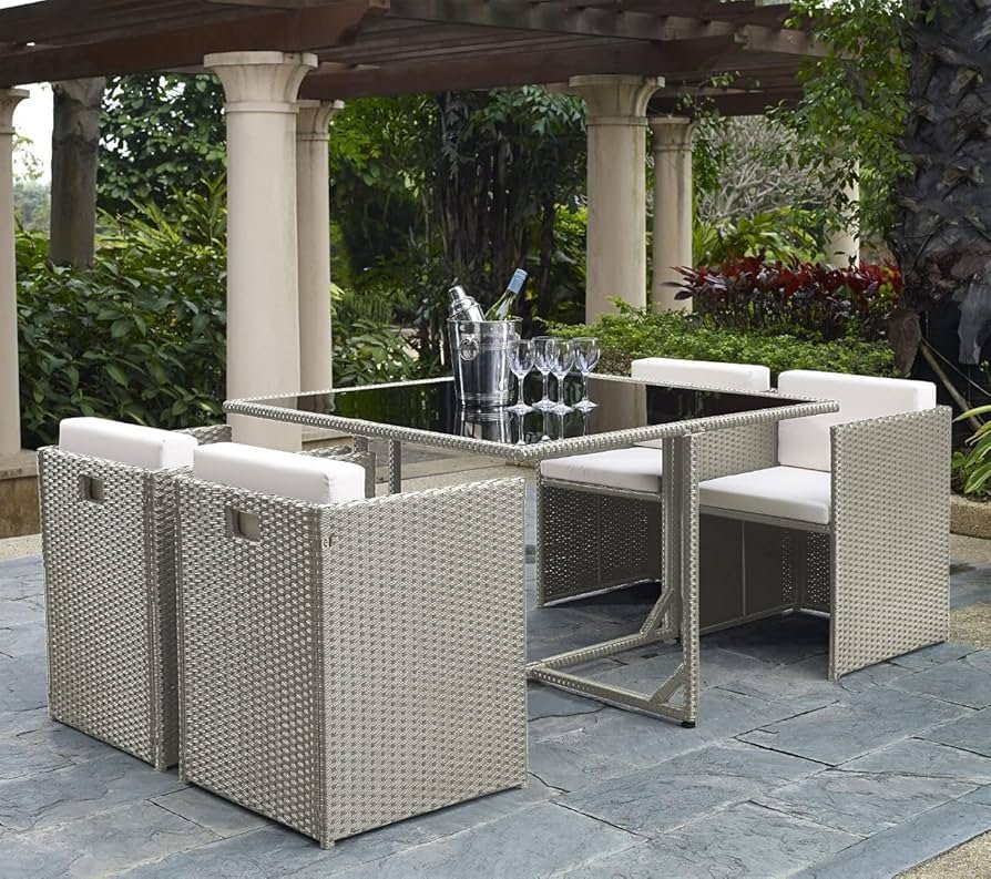 Space-saving rattan cube dining set placed beside a garden flower bed, showing a compact outdoor dining layout