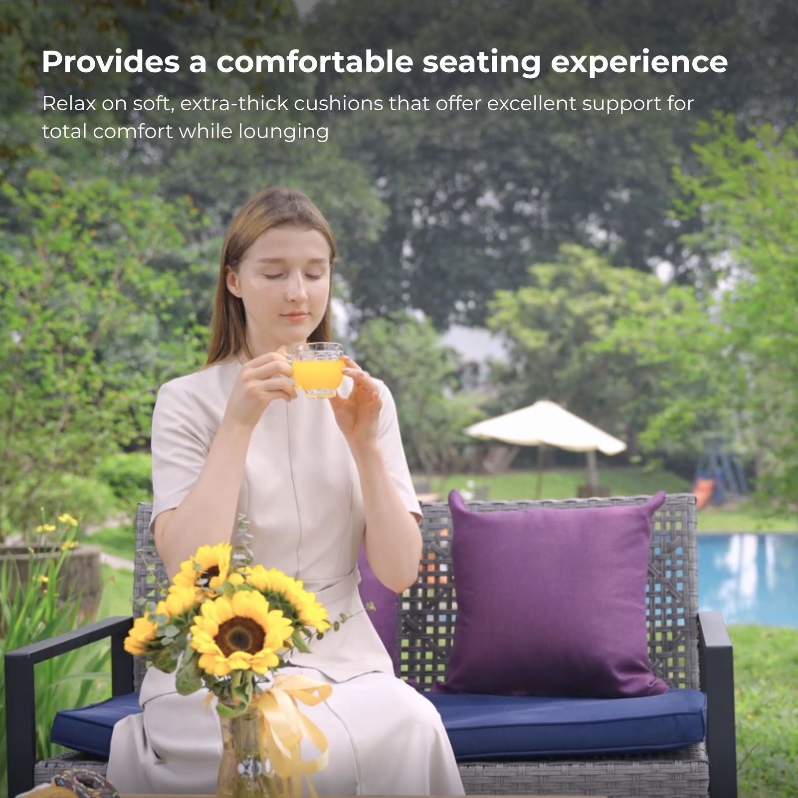 Woman relaxing on gray rattan patio sectional chair with blue cushions enjoying a drink