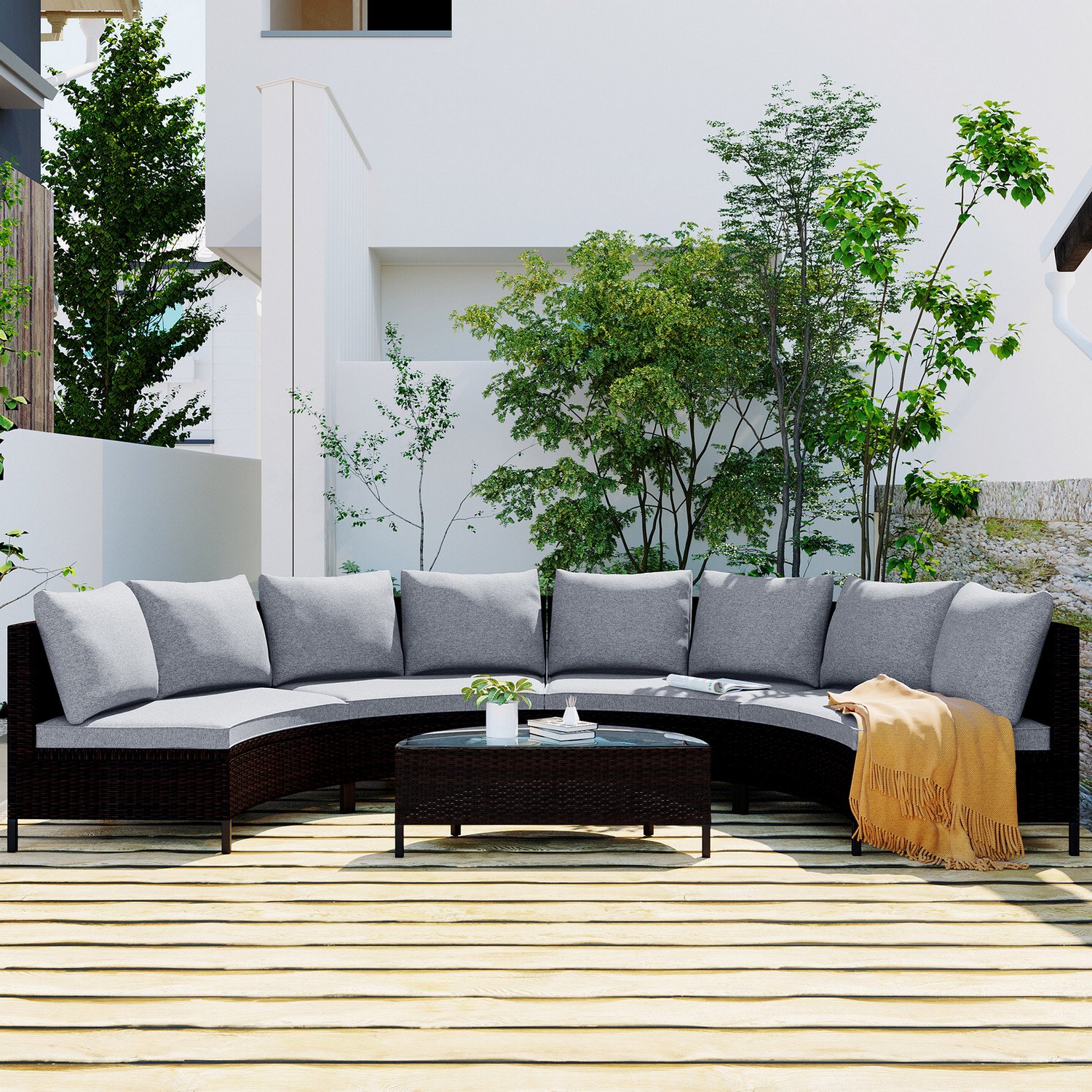 5-piece brown rattan half-moon sectional set styled on outdoor deck with green trees, magazines on table, and blanket on sofa