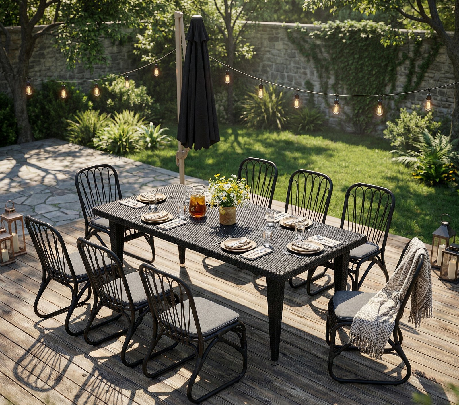 8-seater backyard rattan dining set on a wooden deck with floral centerpiece, tableware, tea set, closed patio umbrella, and warm string lights overhead
