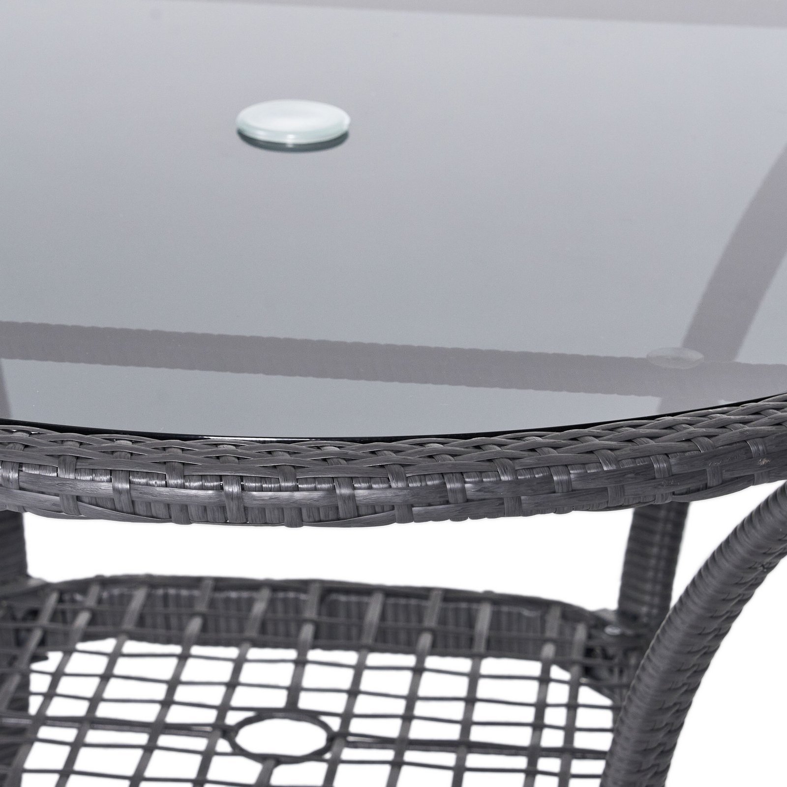 Close-up of gray rattan patio dining table with tempered glass top, umbrella hole, and lower wicker shelf