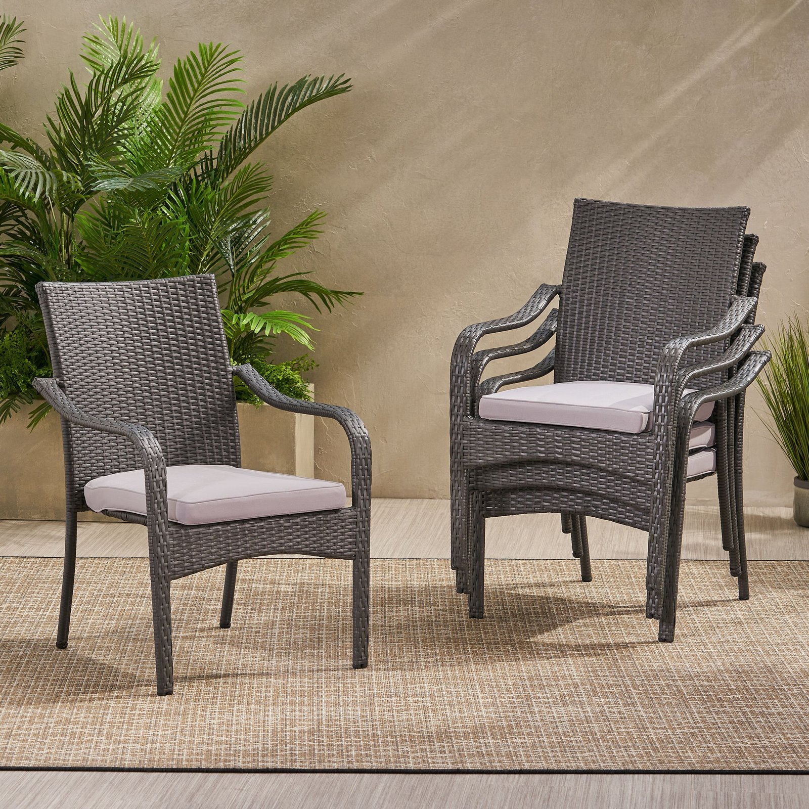 Four stackable gray rattan patio dining chairs placed in backyard