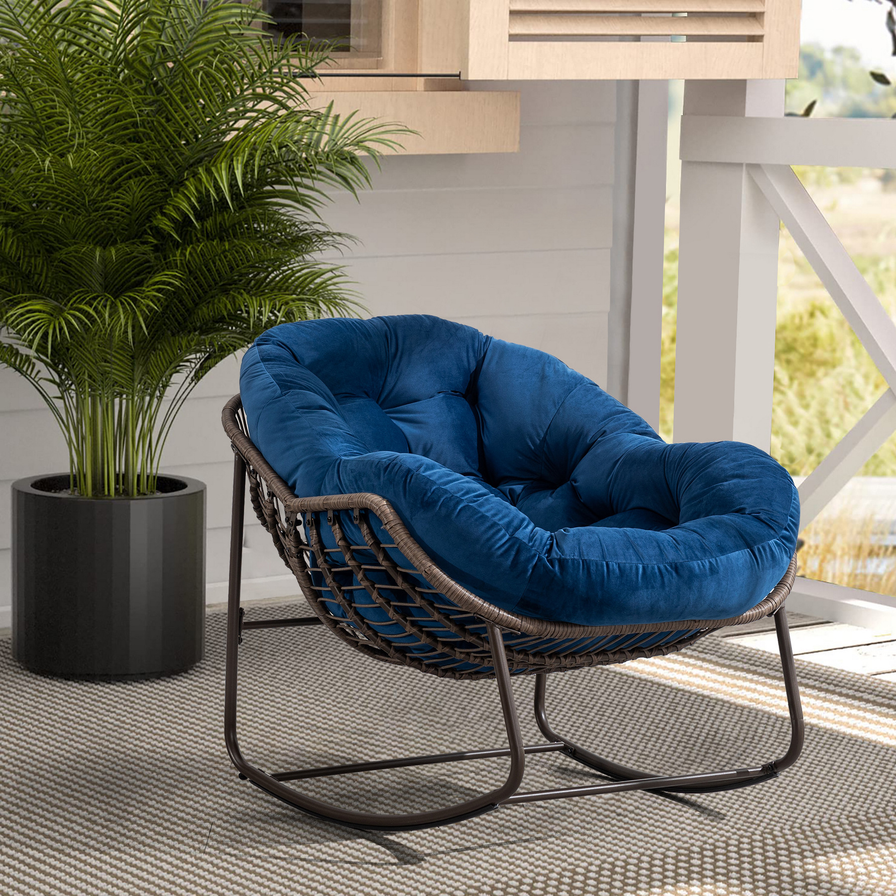 oversized outdoor rattan rocking chair with blue cushion and brown wicker frame