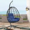 Single person cream PE rattan hanging egg chair with a plush Navy Blue cushion on a sunny farmhouse patio.