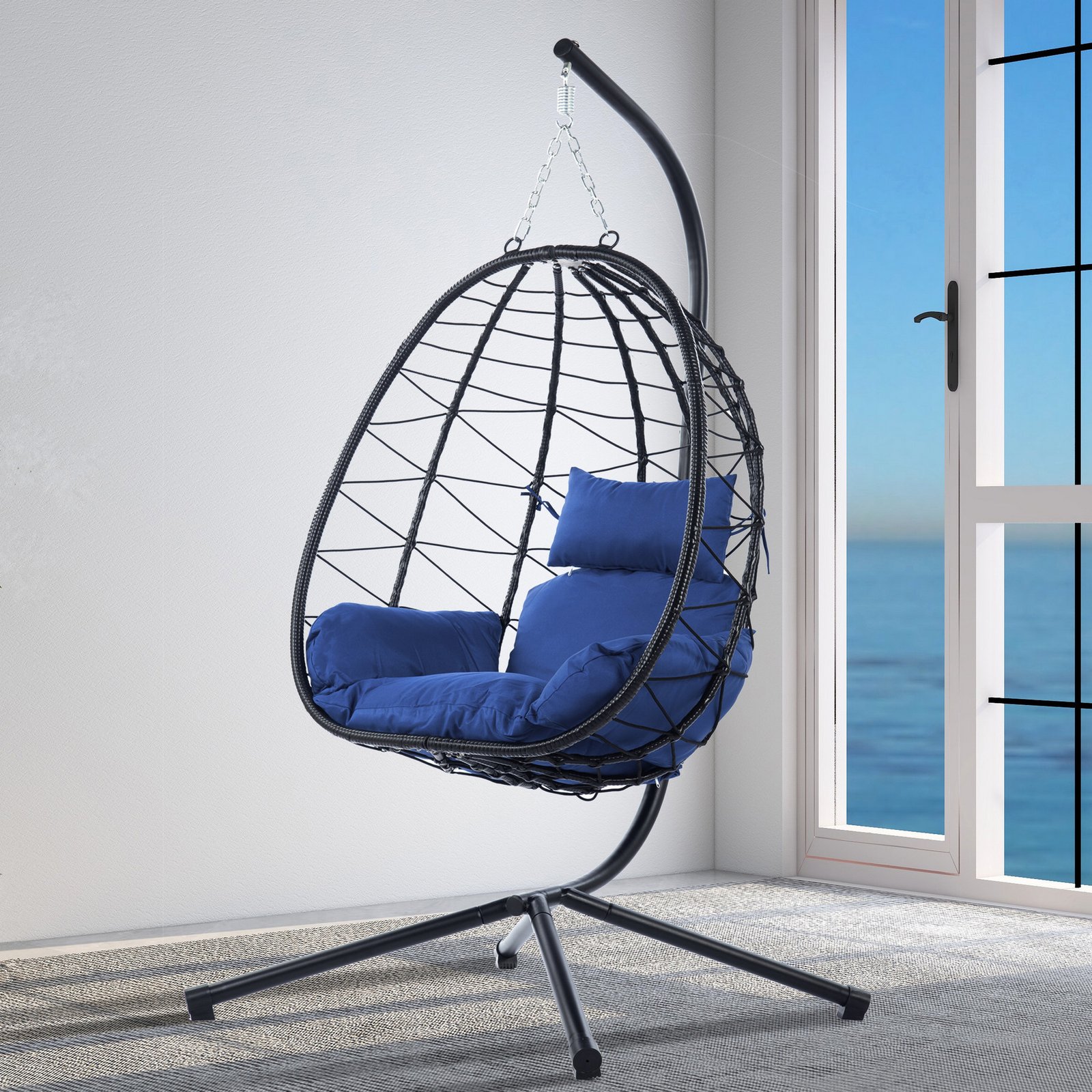 A 45-degree angled view of the wicker hanging egg chair with a plush Navy Blue cushion, beautifully set on a sunny covered patio.