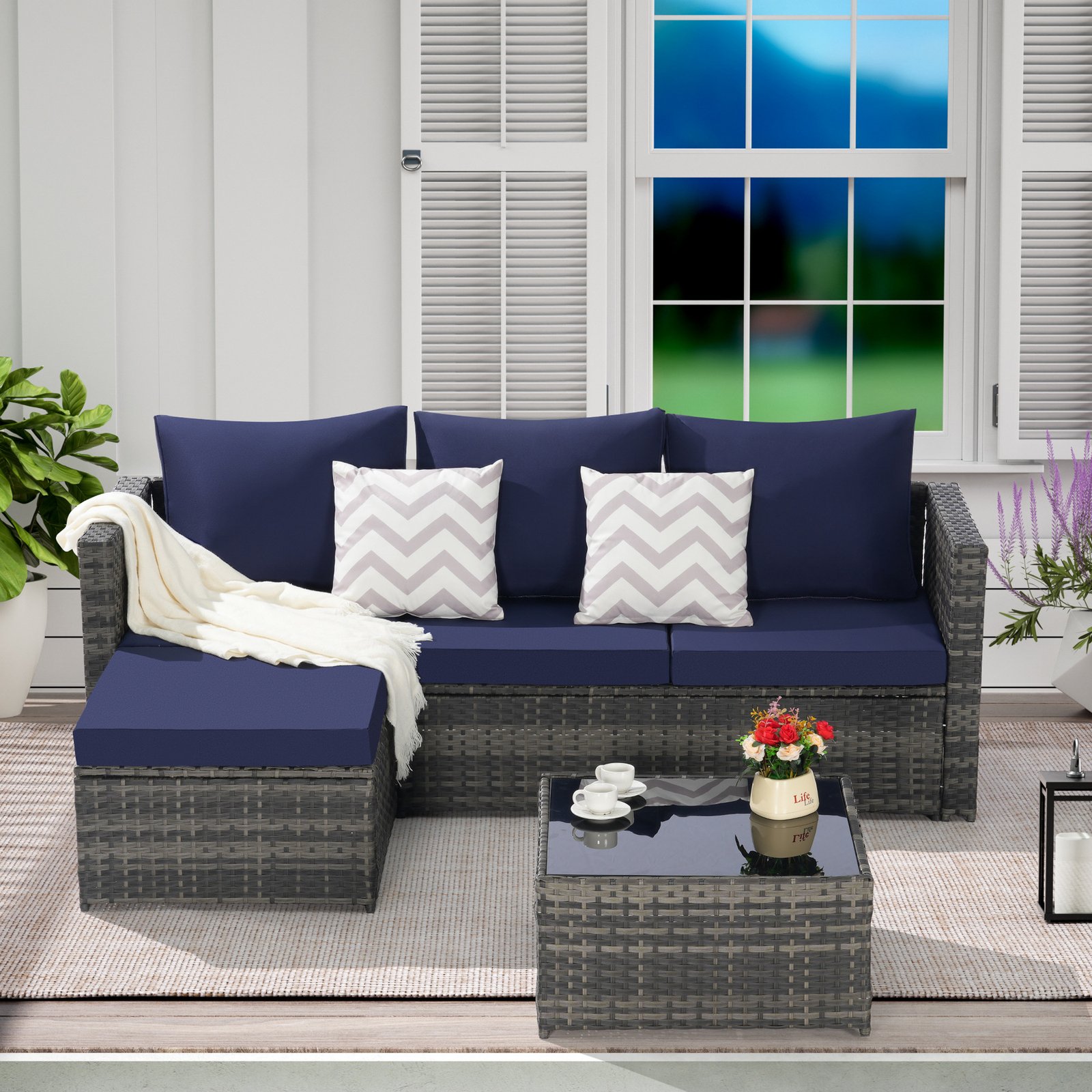 2-Piece L-shaped wicker patio furniture set with dark blue cushions, ottoman and detachable coffee table displayed on an outdoor terrace