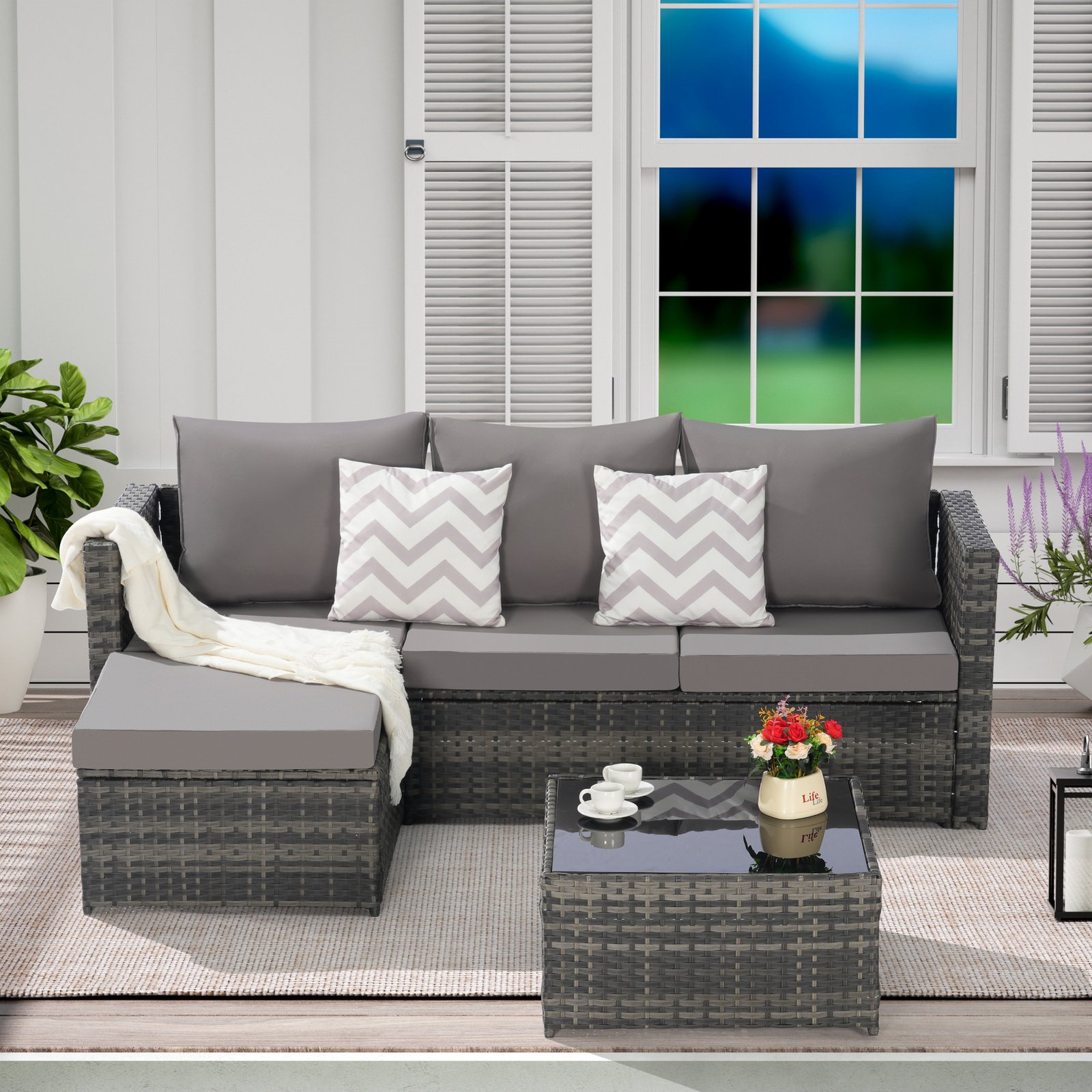 2-Piece L-shaped wicker patio furniture set with dark gray cushions, attached ottoman and detachable coffee table on a terrace setting