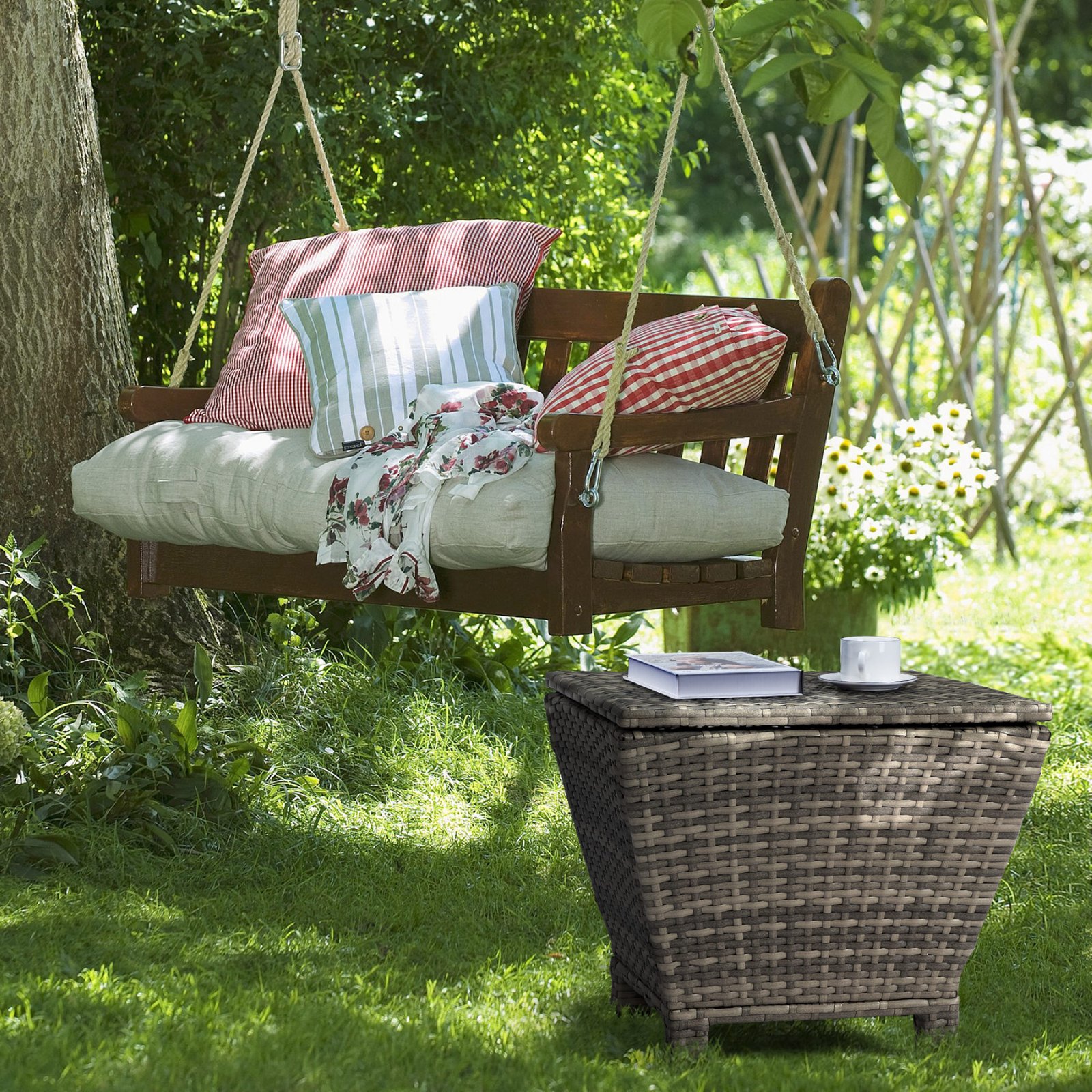 Gray outdoor wicker storage side table placed beside a patio swing chair for outdoor relaxation