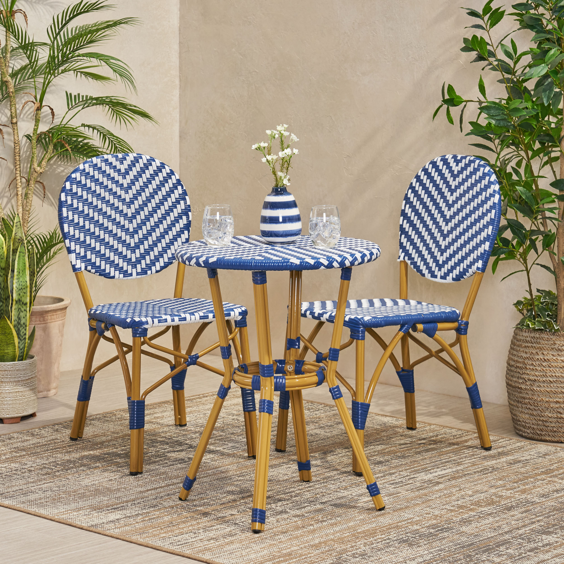 3 piece outdoor French bistro set with navy blue and white PE rattan chairs and round table in a compact outdoor space